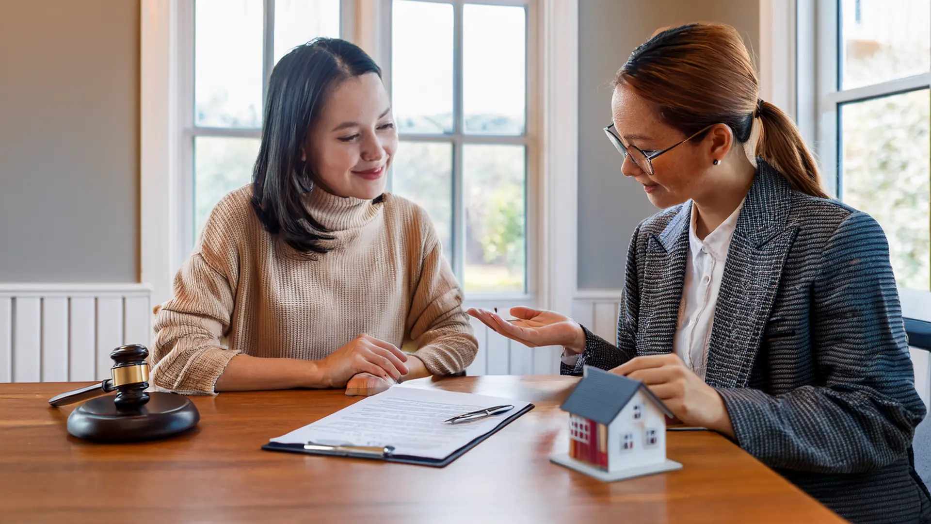 Mortgage broker explaining a page of loan disclosure documents to a first-time buyer at an office desk