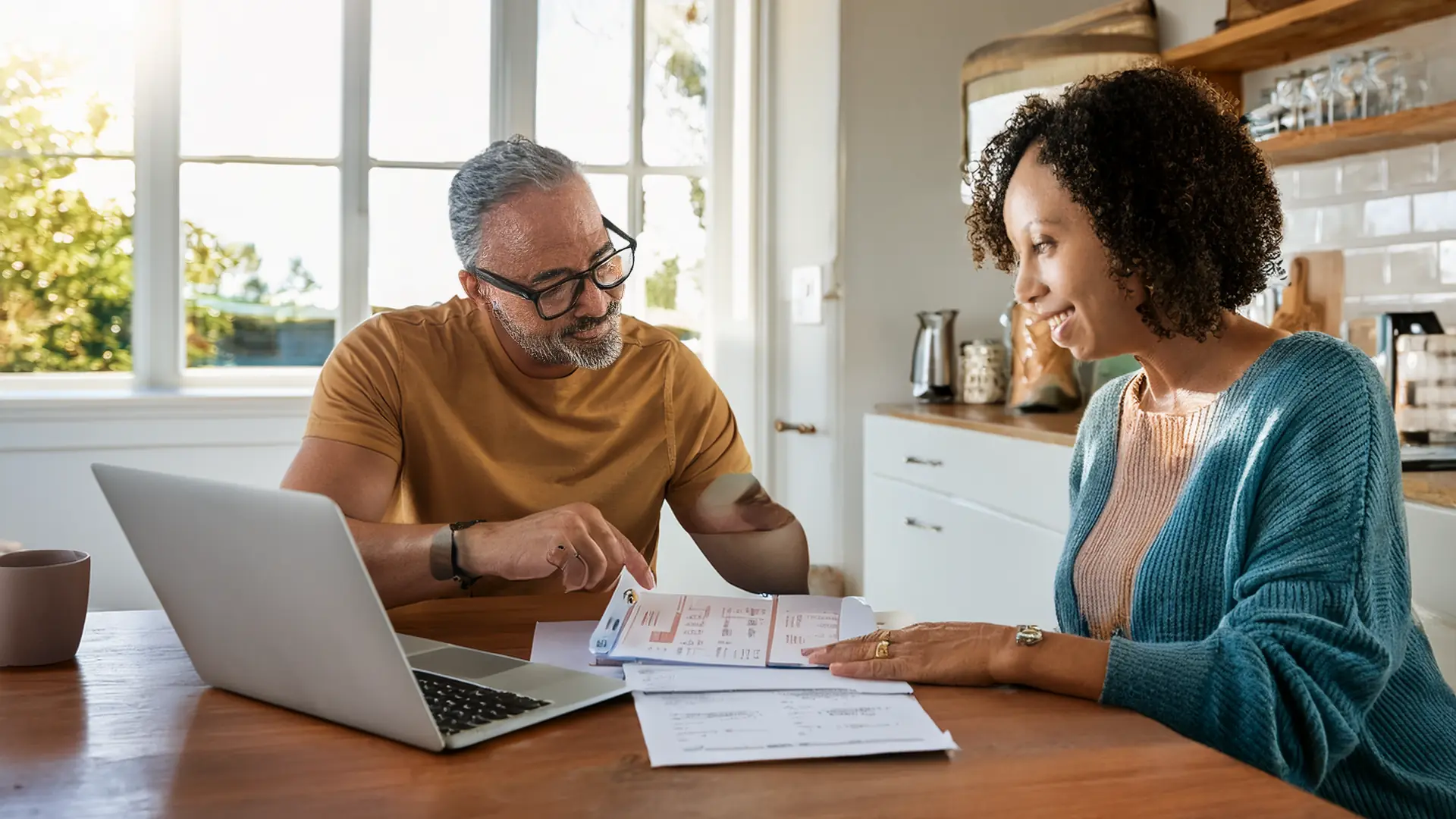 Michigan homeowners reviewing refinance paperwork and a mortgage statement at their kitchen table